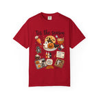 A red short-sleeve crewneck t-shirt featuring a colorful Halloween-themed graphic print on the front with the text 'tis the season' and illustrations of pumpkins, ghosts, treats, and a spiderweb.