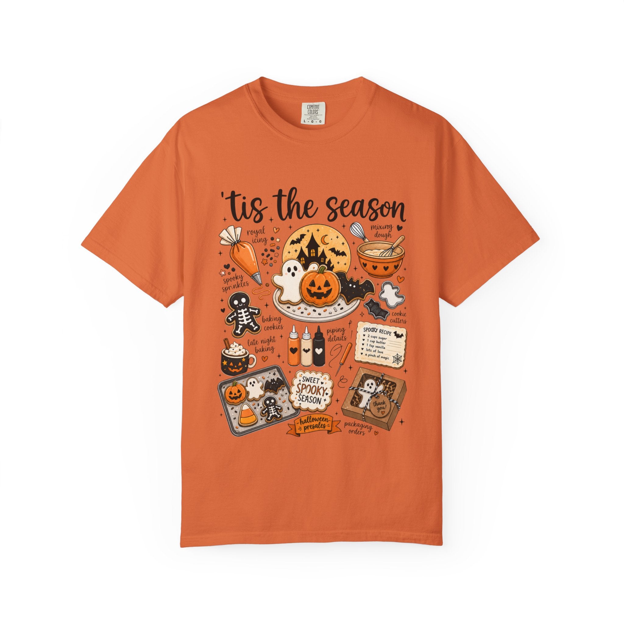 An orange crewneck t-shirt featuring a detailed Halloween graphic print with the text 'tis the season' and various spooky illustrations like pumpkins, ghosts, and a gingerbread man, displayed on a clean white background.