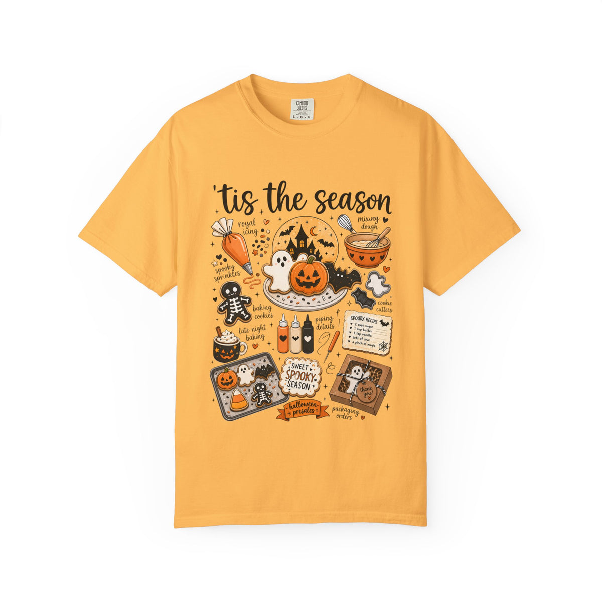 A yellow short-sleeve crewneck t-shirt featuring a colorful Halloween-themed graphic print with the text 'tis the season' and illustrations of jack-o'-lanterns, ghosts, a spider, and spooky treats.