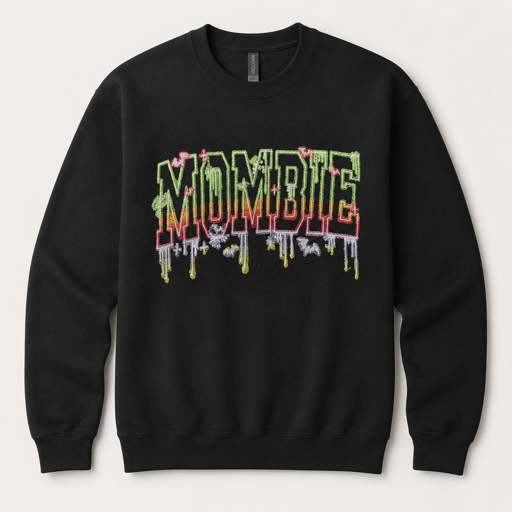 A black crewneck sweatshirt featuring a colorful 'MOMBIE' graphic on the chest in a dripping, layered style with green, red, and yellow tones, set against a light beige background.