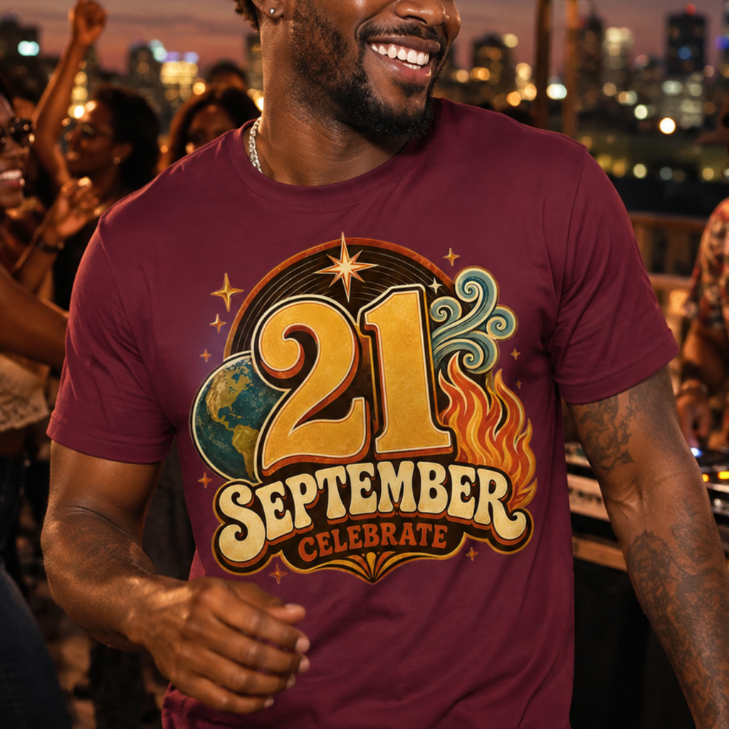 A man smiling on a rooftop party wearing a maroon t-shirt with a '21 September Celebrate' graphic print, with a city skyline and string lights in the background.