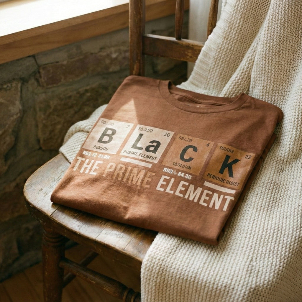 Folded brown t-shirt with text on a wooden surface near a stone wall